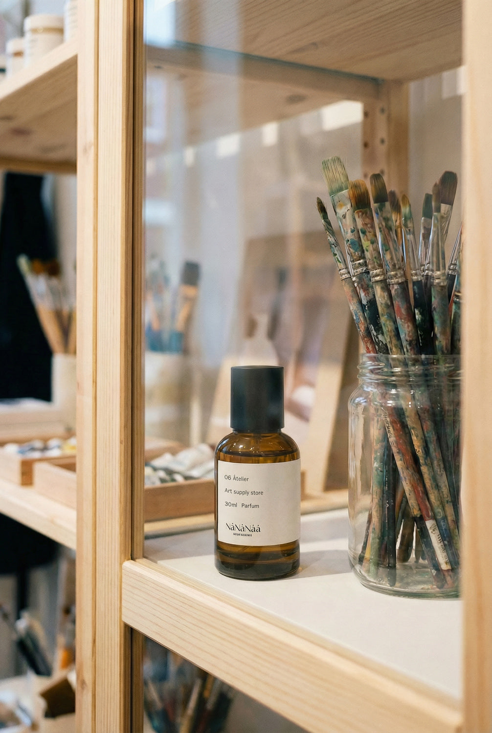 Bottle of perfume and jar of brushes on a wooden shelf